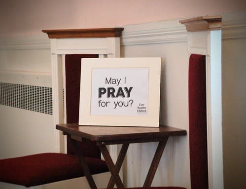 A framed sign in the sanctuary at East Baptist Church reading “May I pray for you?”